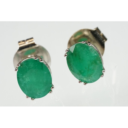 102 - Pair of emerald white metal stud earrings, the oval mixed cut emerald measuring approx 10mm x 8mm, c... 