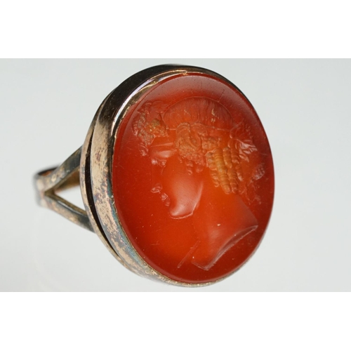 104 - Carnelian intaglio gilt metal ring, the oval carnelian intaglio depicting Roman head facing left, di... 