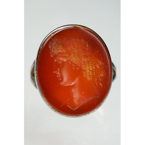 104 - Carnelian intaglio gilt metal ring, the oval carnelian intaglio depicting Roman head facing left, di... 