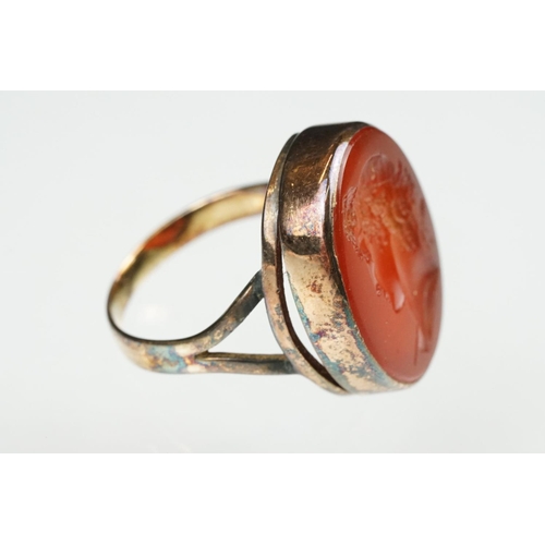 104 - Carnelian intaglio gilt metal ring, the oval carnelian intaglio depicting Roman head facing left, di... 