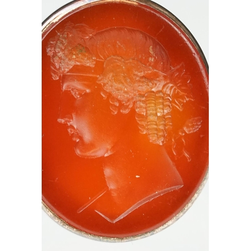 104 - Carnelian intaglio gilt metal ring, the oval carnelian intaglio depicting Roman head facing left, di... 