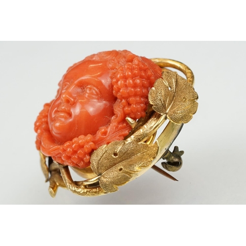 22 - 19th century coral yellow metal brooch and earrings; the brooch with carved coral putti face, surrou... 