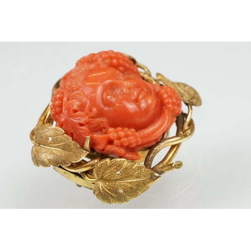 22 - 19th century coral yellow metal brooch and earrings; the brooch with carved coral putti face, surrou... 