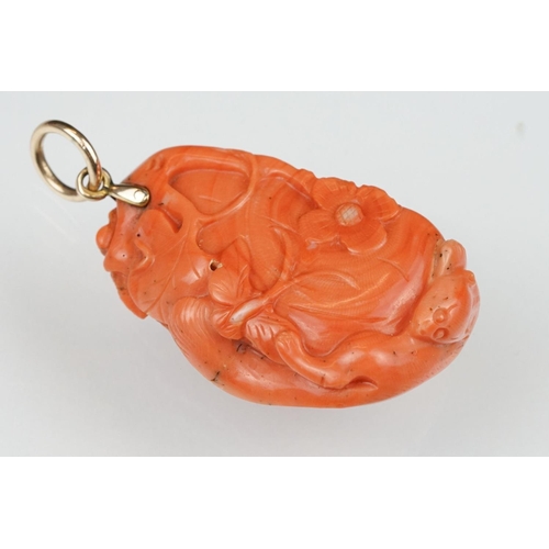 27 - Early 20th century carved coral pendant, the coral depicting long-tailed mammal, butterflies and flo... 