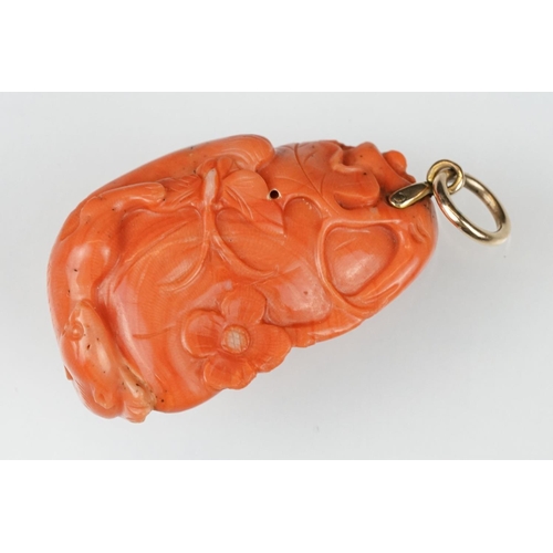 27 - Early 20th century carved coral pendant, the coral depicting long-tailed mammal, butterflies and flo... 