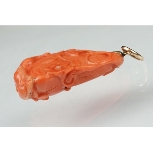 27 - Early 20th century carved coral pendant, the coral depicting long-tailed mammal, butterflies and flo... 