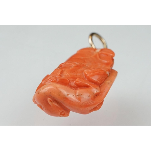 27 - Early 20th century carved coral pendant, the coral depicting long-tailed mammal, butterflies and flo... 