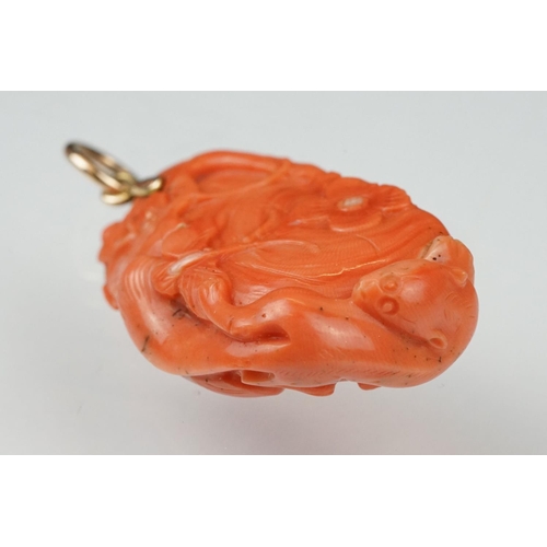 27 - Early 20th century carved coral pendant, the coral depicting long-tailed mammal, butterflies and flo... 