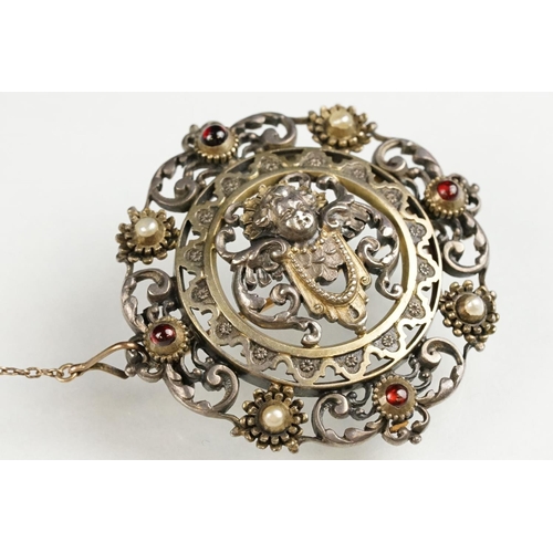 114 - Indian seed pearl and garnet unmarked parcel gilt silver brooch, the centre depicting cast cherub fa... 