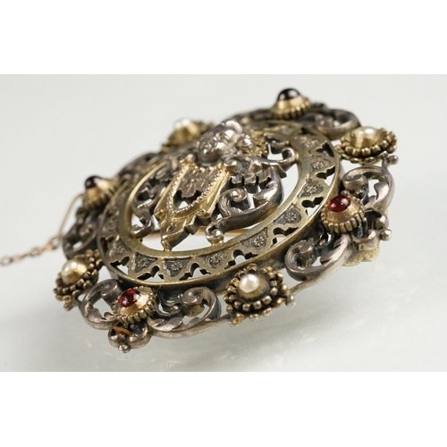 114 - Indian seed pearl and garnet unmarked parcel gilt silver brooch, the centre depicting cast cherub fa... 