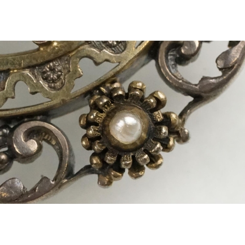 114 - Indian seed pearl and garnet unmarked parcel gilt silver brooch, the centre depicting cast cherub fa... 