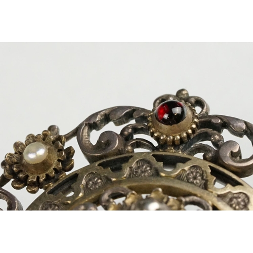 114 - Indian seed pearl and garnet unmarked parcel gilt silver brooch, the centre depicting cast cherub fa... 