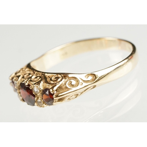 117 - Garnet 9ct yellow gold boat head ring, three graduated round mixed cut rubies, the principal ruby di... 