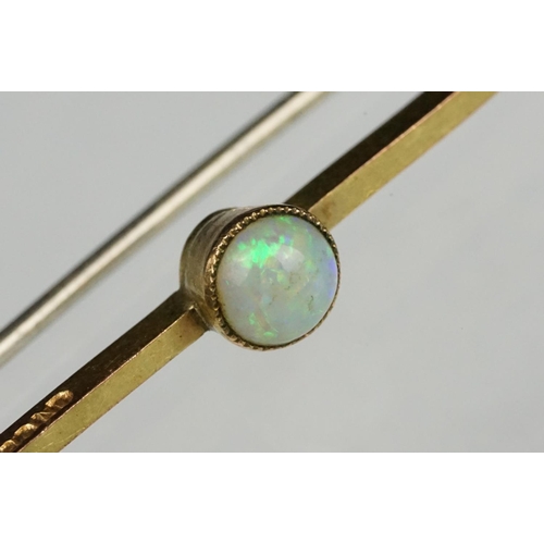 122 - Precious white opal 9ct gold bar brooch, the round cabochon cut opal displaying indigo, yellow, gree... 