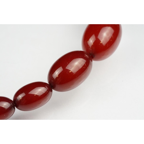 51 - Cherry amber Bakelite graduated bead necklace, sixty four oval beads, the largest measuring approx 3... 