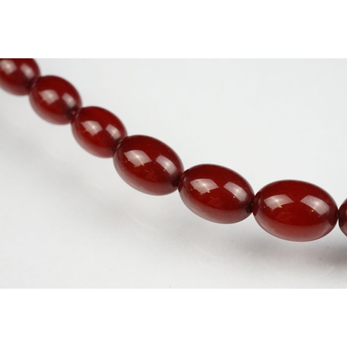 51 - Cherry amber Bakelite graduated bead necklace, sixty four oval beads, the largest measuring approx 3... 