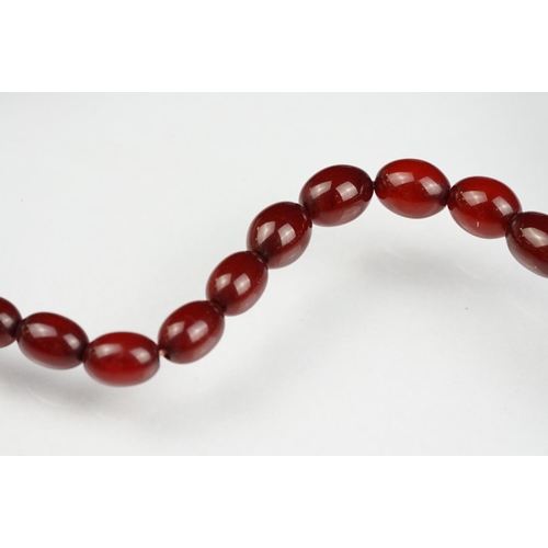 51 - Cherry amber Bakelite graduated bead necklace, sixty four oval beads, the largest measuring approx 3... 