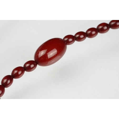 51 - Cherry amber Bakelite graduated bead necklace, sixty four oval beads, the largest measuring approx 3... 