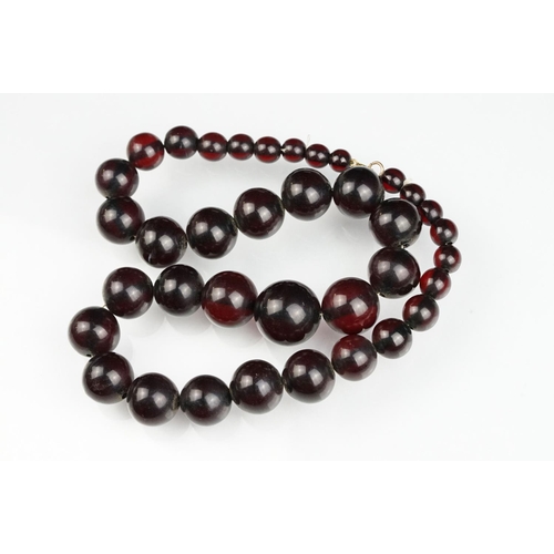 51 - Cherry amber Bakelite graduated bead necklace, sixty four oval beads, the largest measuring approx 3... 