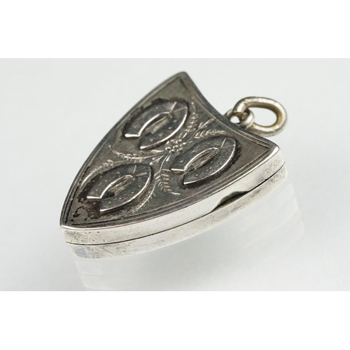 87 - Late Victorian silver shield shaped locket with three horseshoes in relief, zigzag detail verso, mak... 