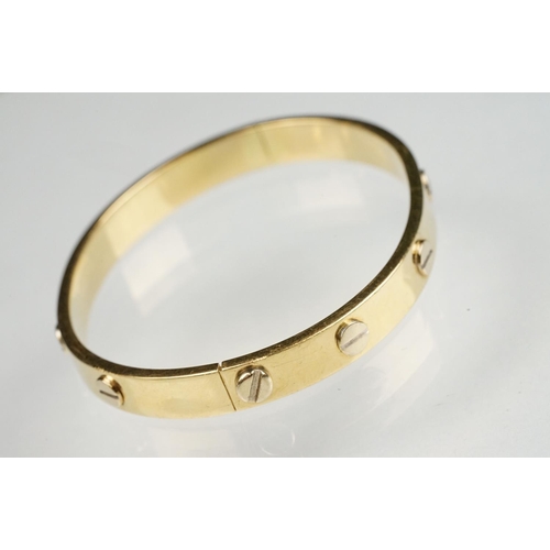 89 - 18ct yellow and white gold hinged band, screw head decoration, the fastening modelled as a screw, wi... 