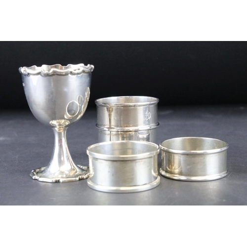 811 - Three silver hallmarked napkin rings and a silver hallmarked egg cup. The egg cup having a gilt inte... 