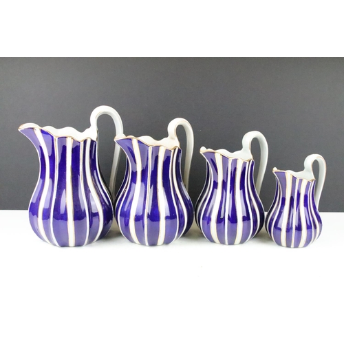 44 - Set of four graduating pottery jugs with gilt, blue & white striped design (tallest approx 22.5cm), ... 