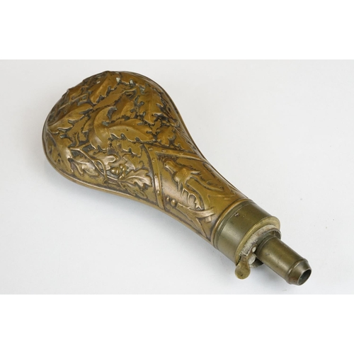 226 - An antique brass powder flask with oak leaf and stag decoration.