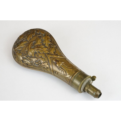 226 - An antique brass powder flask with oak leaf and stag decoration.