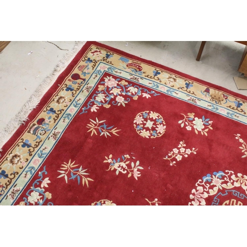 711 - Large Chinese style Red Ground Rug decorated with flowers within a pale green border decorated with ... 