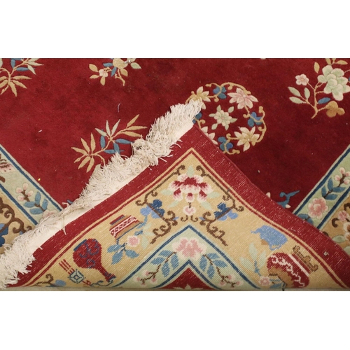 711 - Large Chinese style Red Ground Rug decorated with flowers within a pale green border decorated with ... 