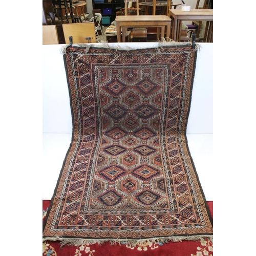 686 - Eastern Wool Red Ground Rug decorated with geometric pattern within a border, 214cm x 132cm