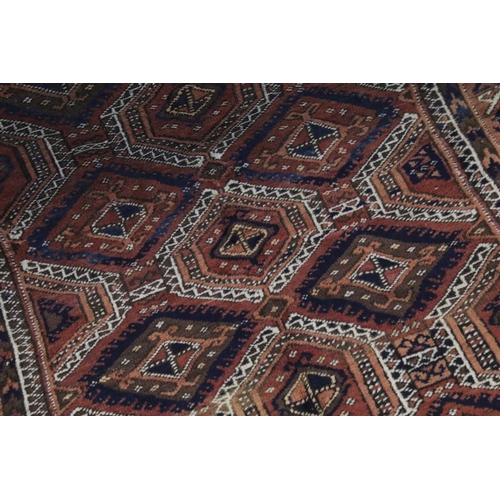 686 - Eastern Wool Red Ground Rug decorated with geometric pattern within a border, 214cm x 132cm