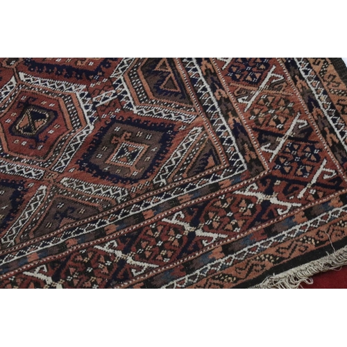 686 - Eastern Wool Red Ground Rug decorated with geometric pattern within a border, 214cm x 132cm