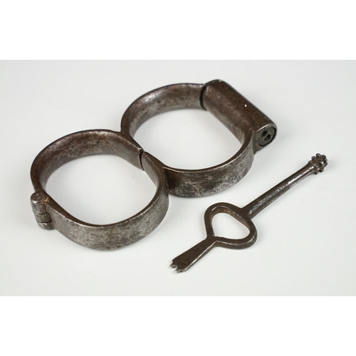 144 - Pair of 19th century steel handcuffs, approx 13cm wide, with key