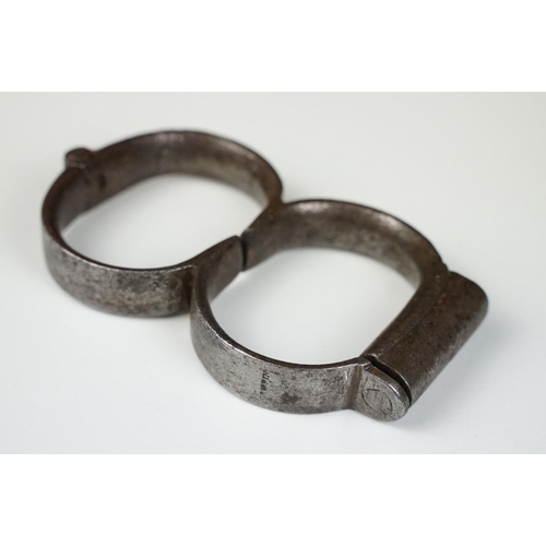 144 - Pair of 19th century steel handcuffs, approx 13cm wide, with key