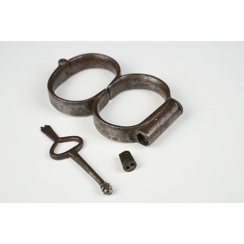 144 - Pair of 19th century steel handcuffs, approx 13cm wide, with key