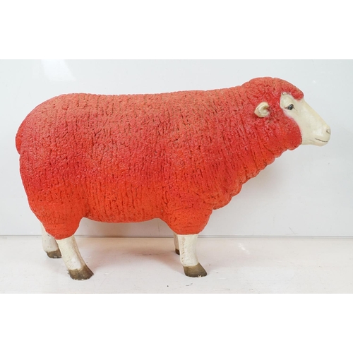 166 - Large painted fibreglass model of a sheep, in red & white. Measures approx 65cm H x 100cm L