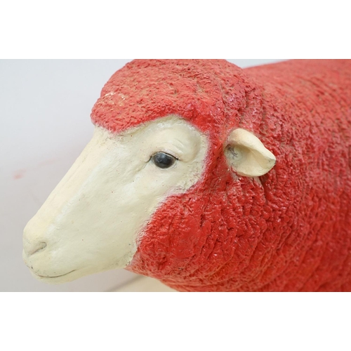 166 - Large painted fibreglass model of a sheep, in red & white. Measures approx 65cm H x 100cm L