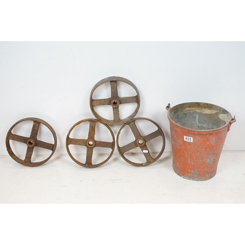 433 - Red painted metal fire bucket containing four cast iron spoked wheels (approx 23.5cm diameter), toge... 