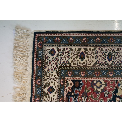 694 - Dark Blue and Pink Ground Rug decorated with flowers and geometric patterns within a cream ground bo... 