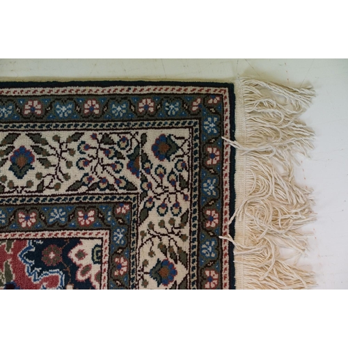 694 - Dark Blue and Pink Ground Rug decorated with flowers and geometric patterns within a cream ground bo... 