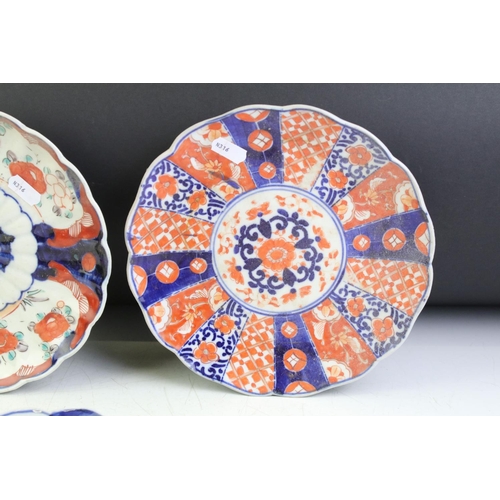 83 - Three 19th Century Japanese Imari plates having blue and white under glazed panelled details and red... 