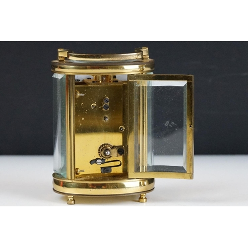 273 - A brass cased carriage clock of oval form with beveled glass panels retailer marked for Chas Frodsha... 