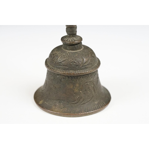 190 - An oriental bronze hand bell with figural finial and engraved decoration.