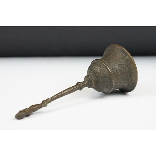 190 - An oriental bronze hand bell with figural finial and engraved decoration.