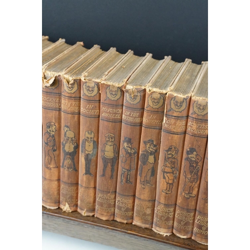 131 - Set of 25 ' Punch Library of Humour ' books, housed on a wooden book trough, approx 64cm wide