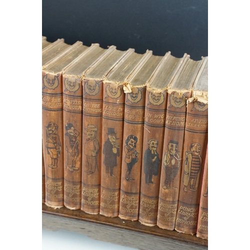 131 - Set of 25 ' Punch Library of Humour ' books, housed on a wooden book trough, approx 64cm wide