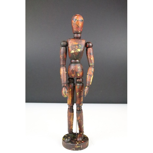 134 - Wooden artists posable drawing aid figure raised on a round wooden base. Measures 33cm tall.