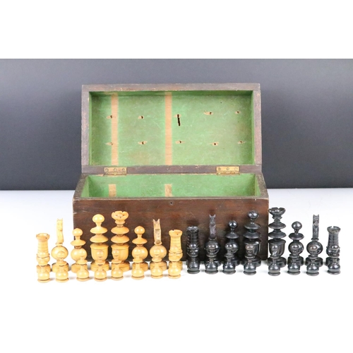 267 - A turned wooden chess set within an antique wooden box, queen stands approx 9cm in height.